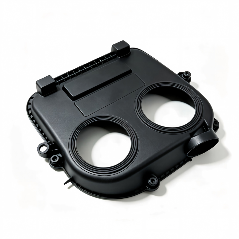 Black timing belt cover with two circular openings and mounting tabs