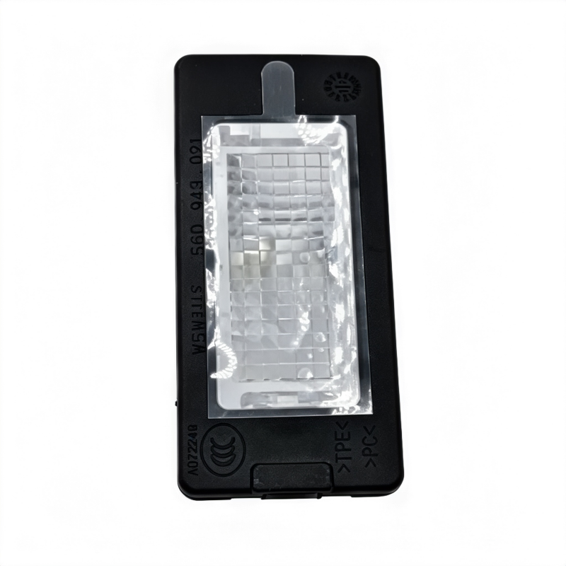 Black license plate light with clear lens and mounting tab, front view