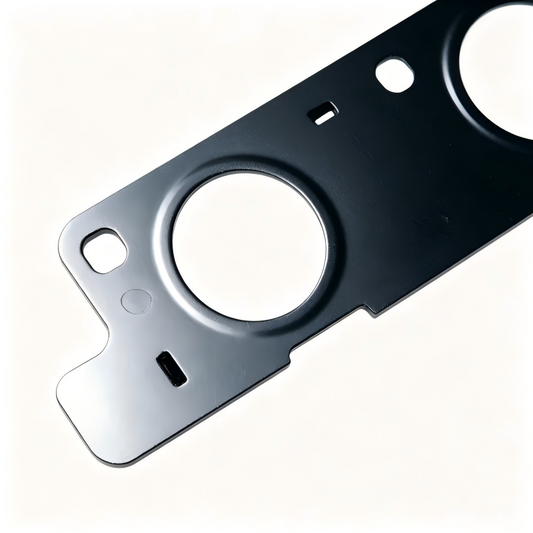 Exhaust manifold gasket metal plate with round cutout and mounting slots, dark finish