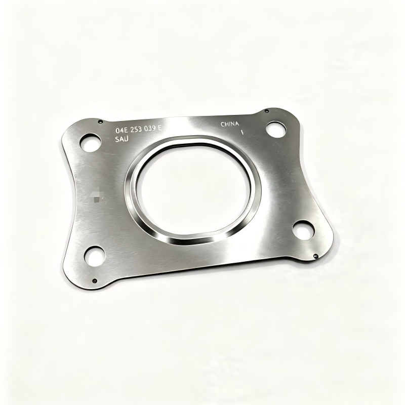 Exhaust manifold gasket, silver metal plate with circular opening and four bolt holes.