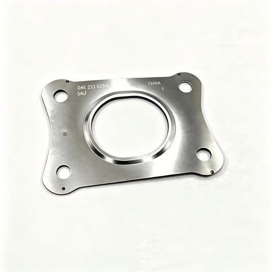 Exhaust manifold gasket, silver metal plate with circular opening and four bolt holes.