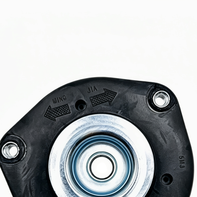 Black front strut mount top view with stamped markings, silver center bearing and bolt