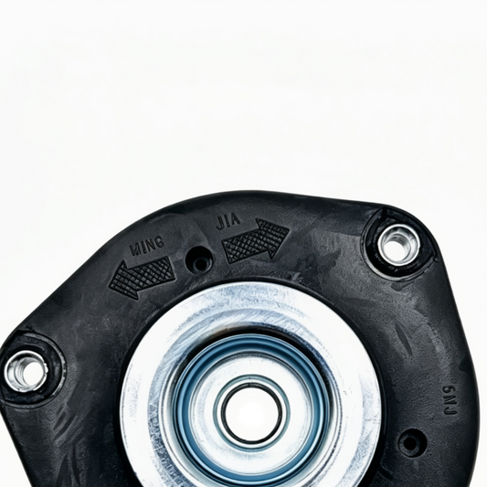 Black front strut mount top view with stamped markings, silver center bearing and bolt