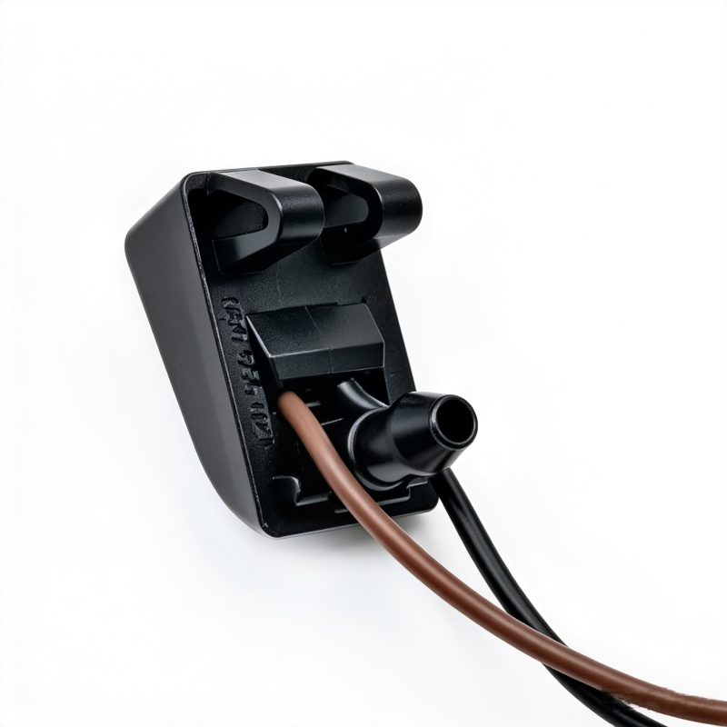 Windshield washer nozzle housing with nozzle port and connected brown and black hoses
