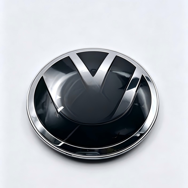 Chrome-and-black grille emblem with dark center V and reflective edge
